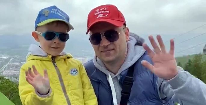 Man and boy both wearing sunglasses and cap waving at the camera